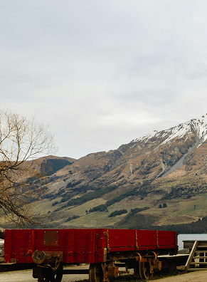 Scenic landscape with mountains, partly covered in snow, and a train in the foreground.