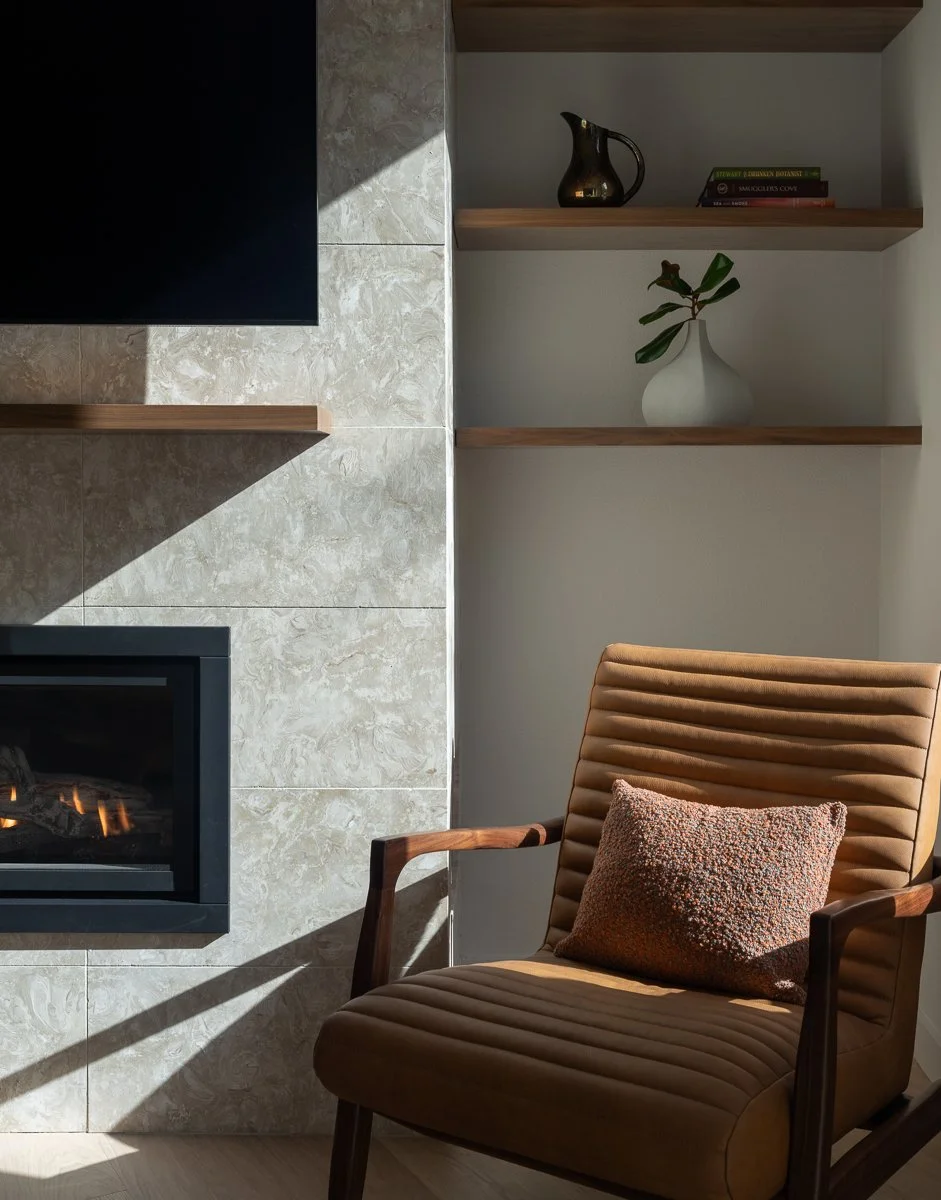 Bainbridge Island interior photography of a luxury condo fireplace nook with walnut shelving, marble tile, and editorial lighting by Emily Barrows.