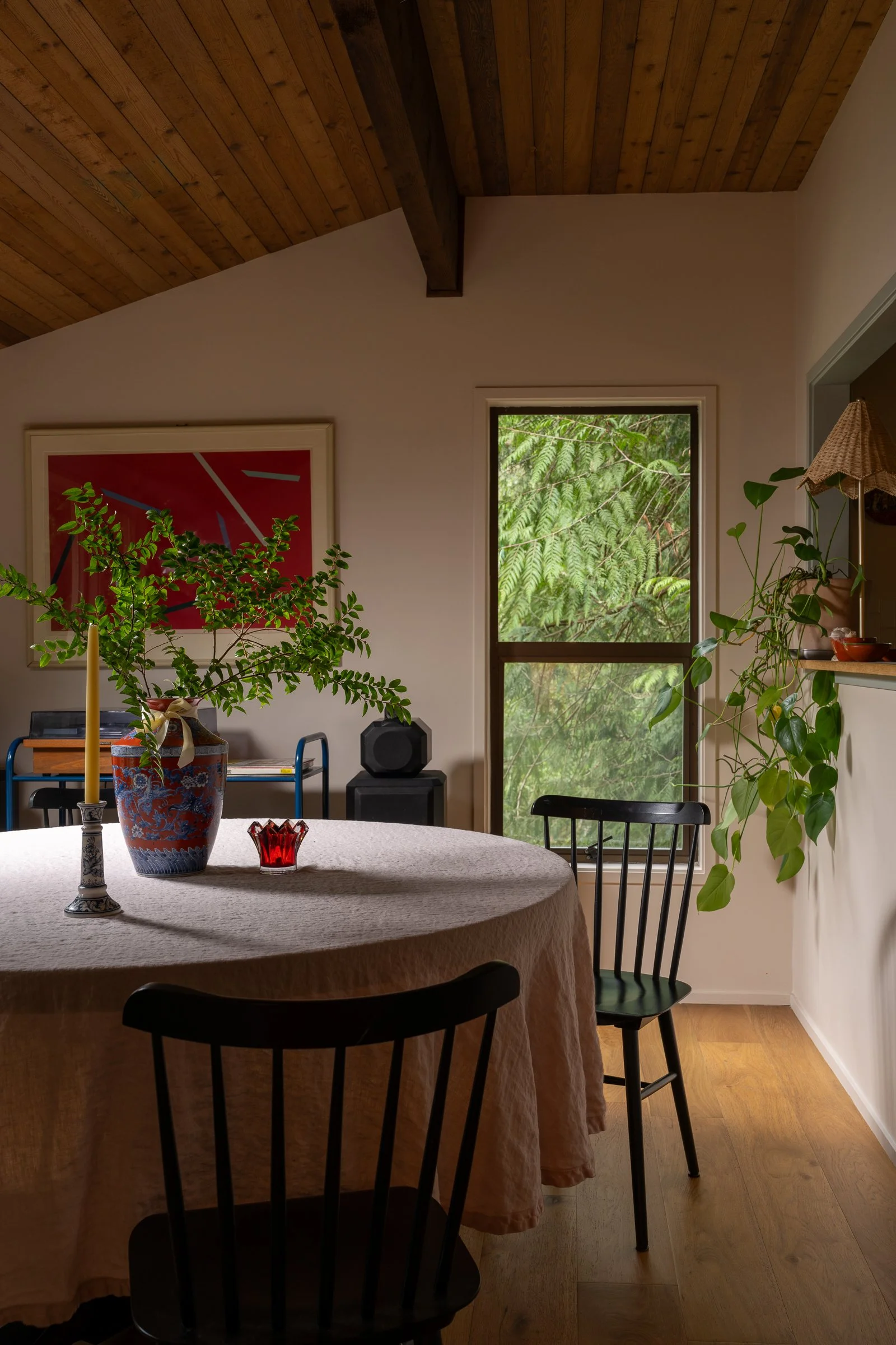 Professional interior photography of a Bainbridge Island modern cabin dining room featuring sloped wood ceilings and lush Pacific Northwest views.