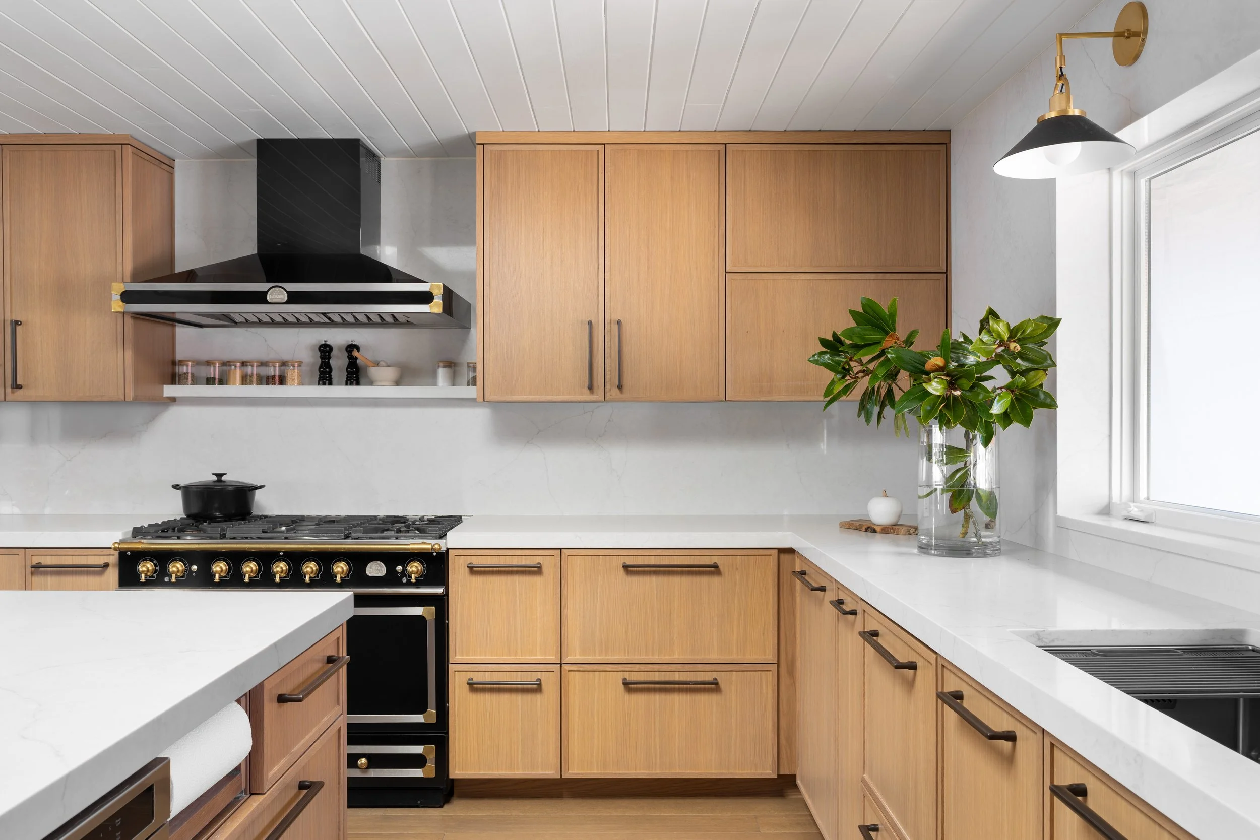 Gig Harbor, WA | Kitchen Remodel | Contemporary quartz countertops pair with blonde wood cabinets and black range.