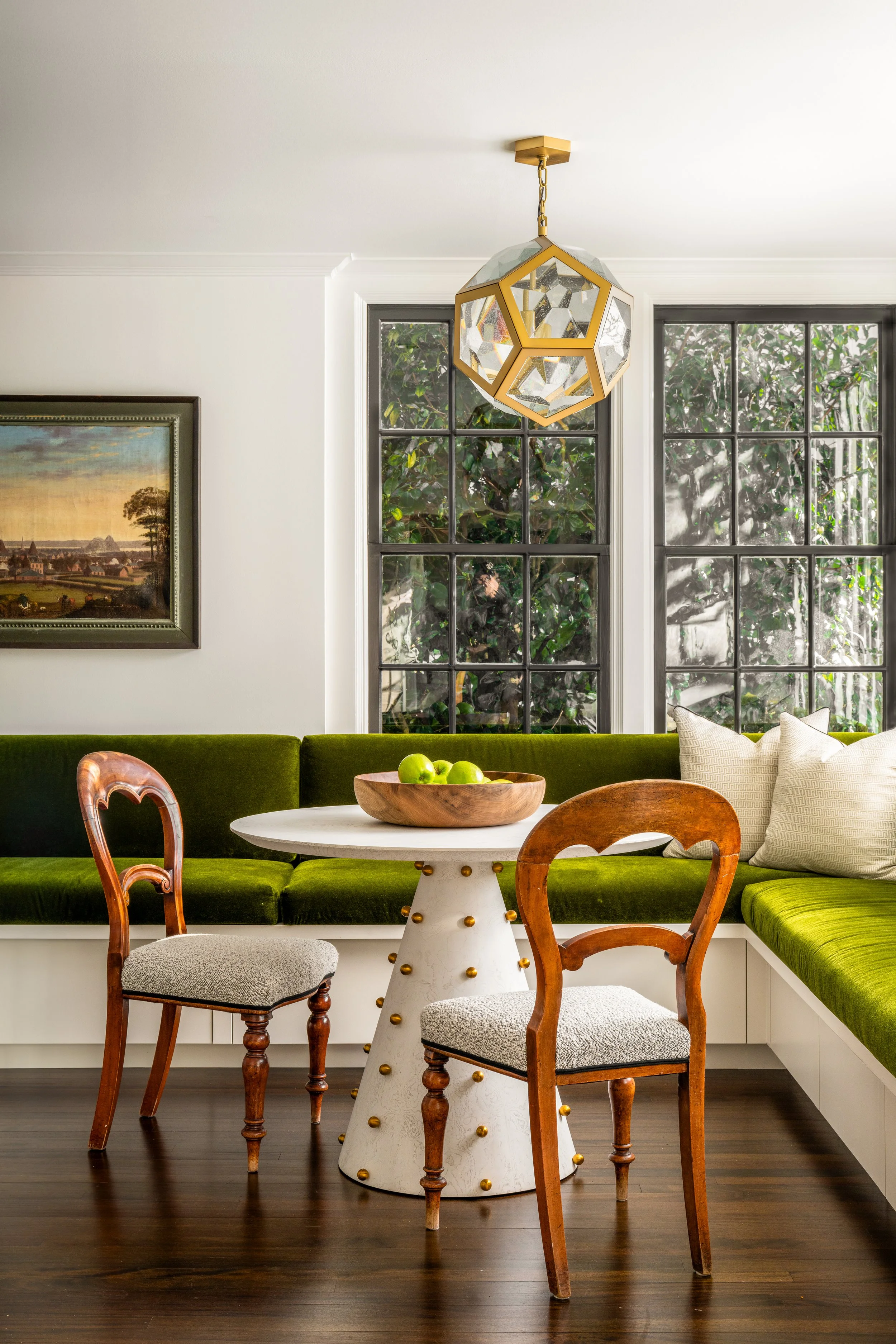 Modern Seattle breakfast nook by Emily Barrows Photography featuring a green velvet banquette, geometric brass pendant, and studded pedestal table.