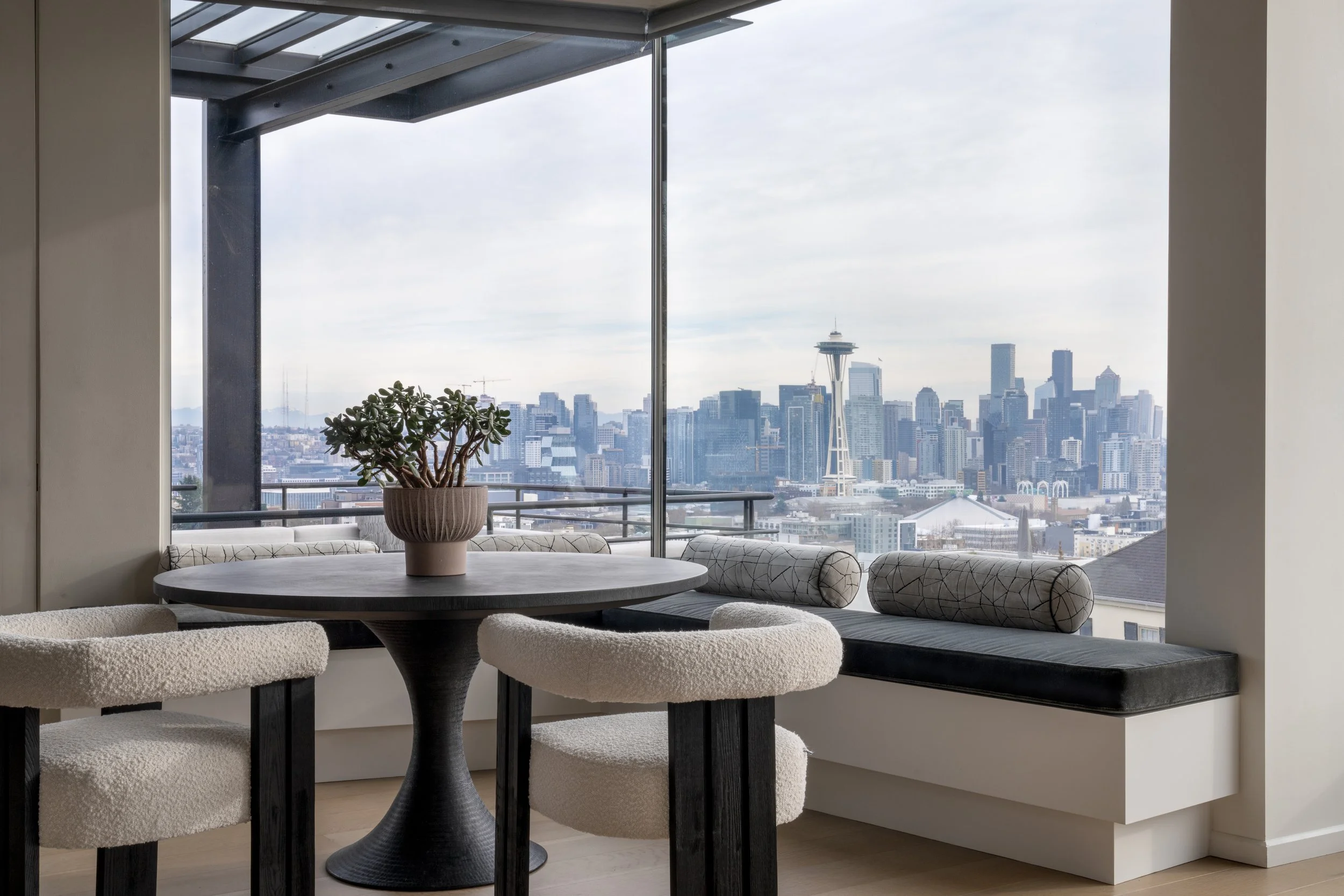 Remodeled dining room with table, chairs and banquette overlooking Seattle, WA skyline. 