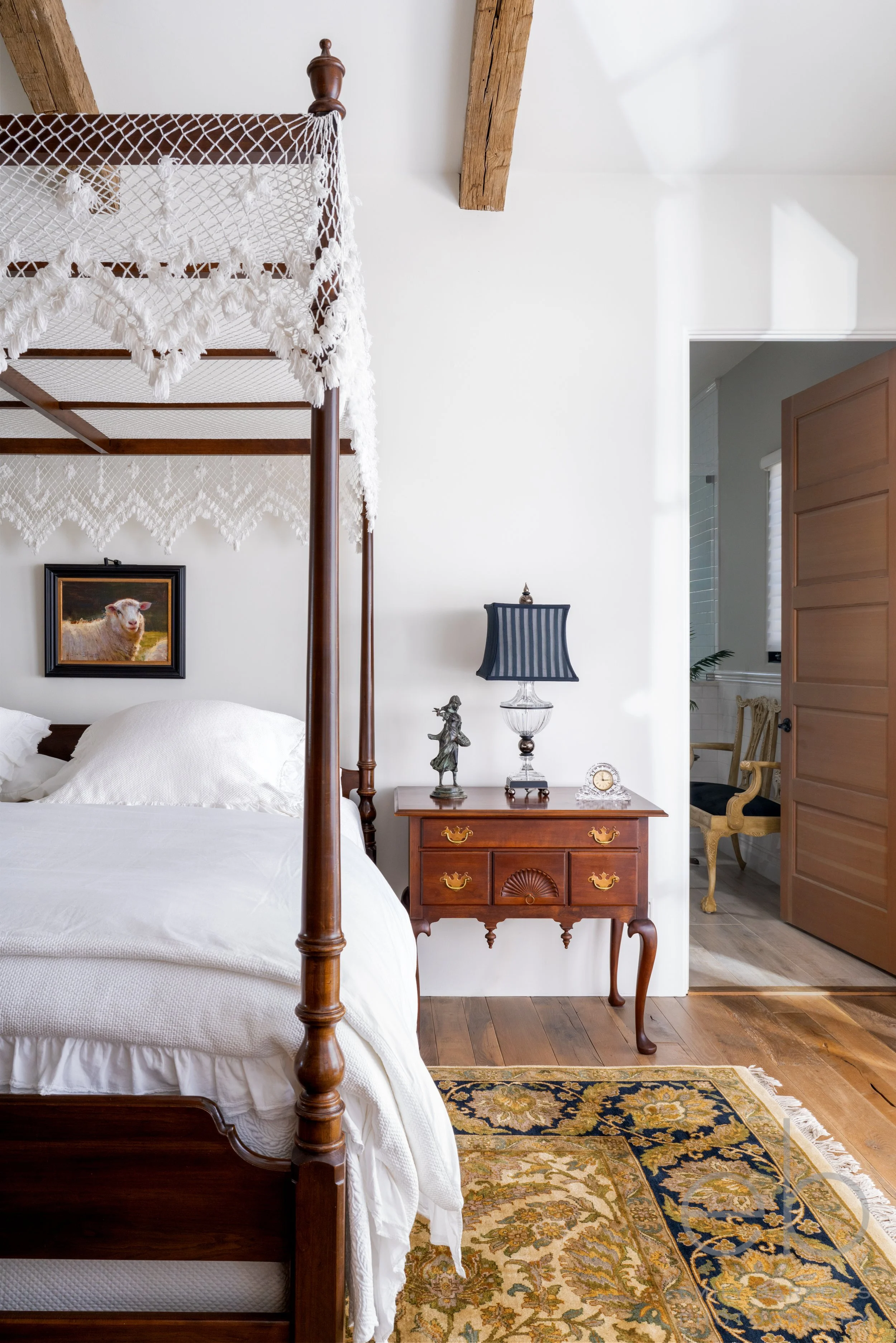 Texas Hill Country | Primary Bedroom Design | Canopy Bed and nightstand beneath ceiling with wood beams