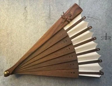 A wooden fan with carved details, partially open showing multiple slats.