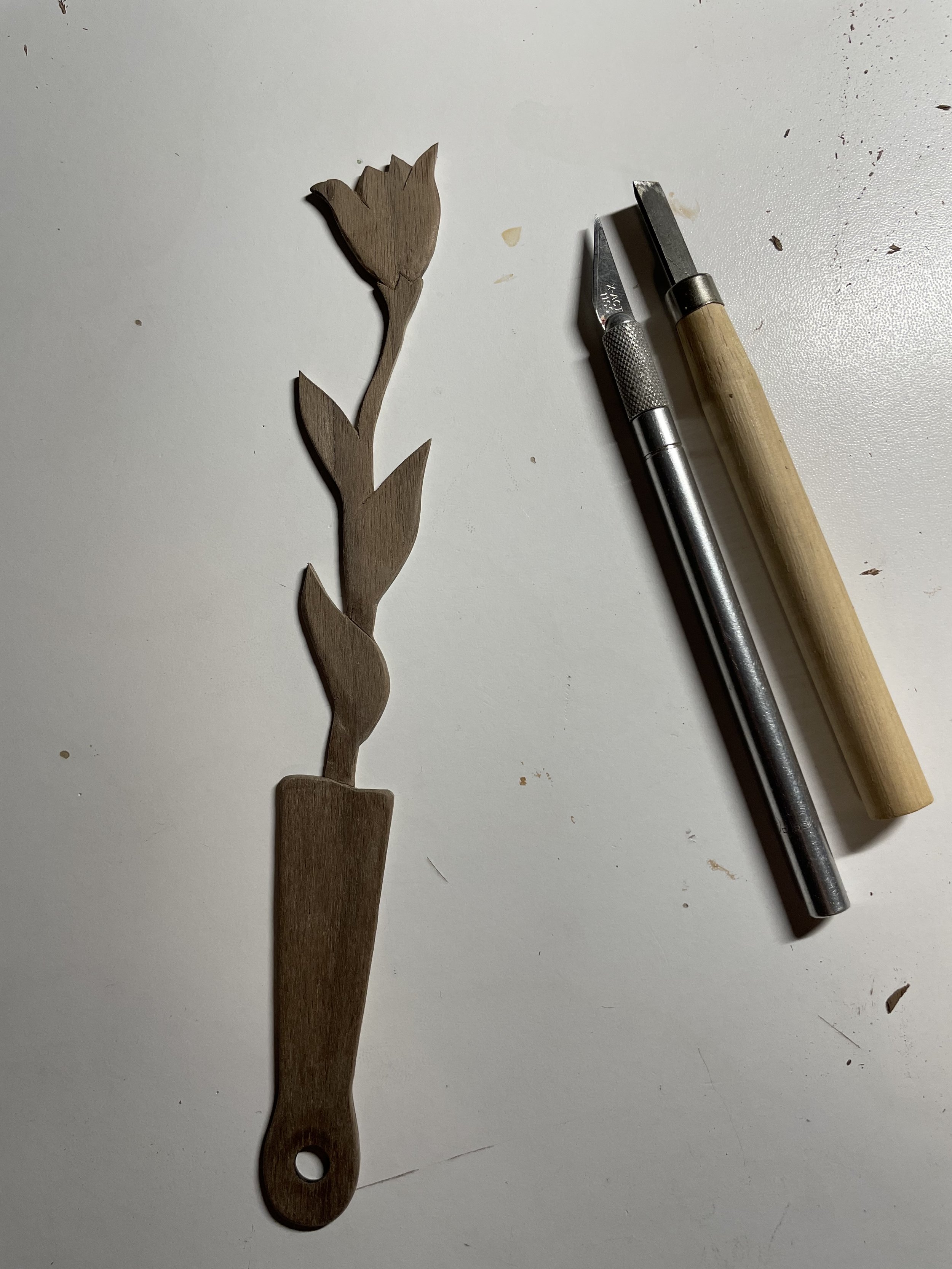 Wooden floral carvings with carving tools on a white surface.