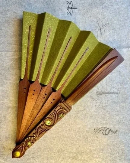 A decorative hand fan with wooden spokes and green fabric.