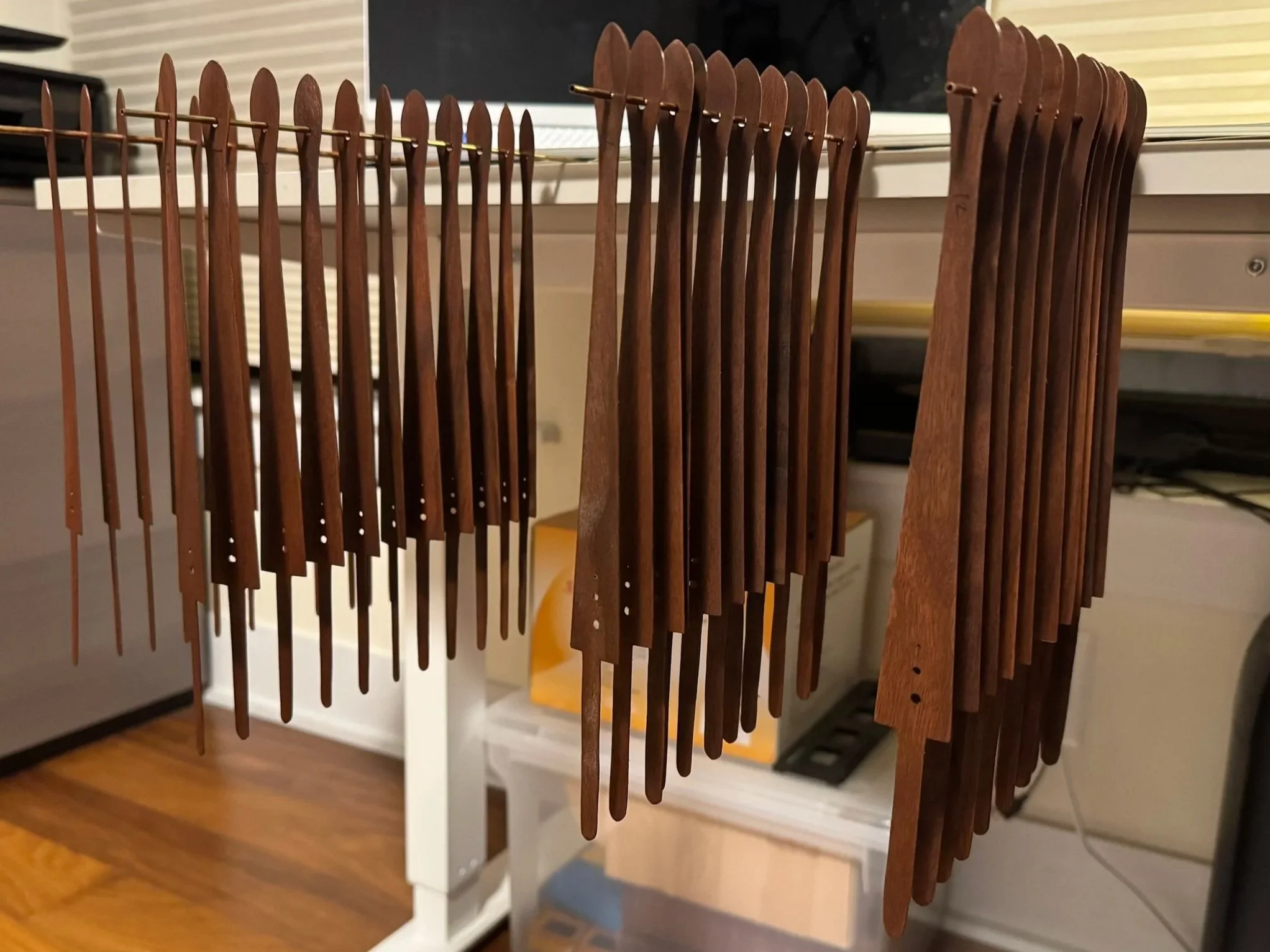 Collection of wooden fan staves drying after staining hanging on a wire rack.