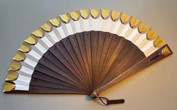 Decorative hand fan with alternating black and white sections, decorated with small lemon wedge accents.
