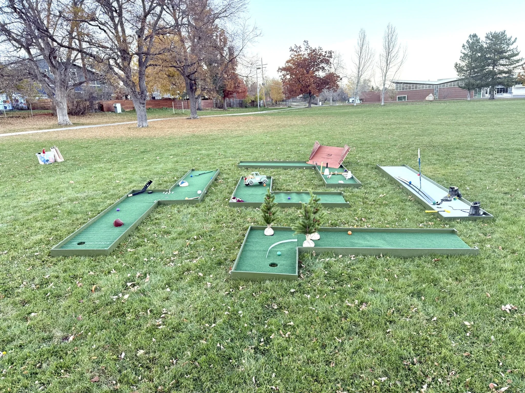 Portable mini golf set up with multiple holes and themes including Red Rocks Amphitheater, skiing, Colorado sports teams, autumn vintage farm truck, and fall pumpkins. For rent.