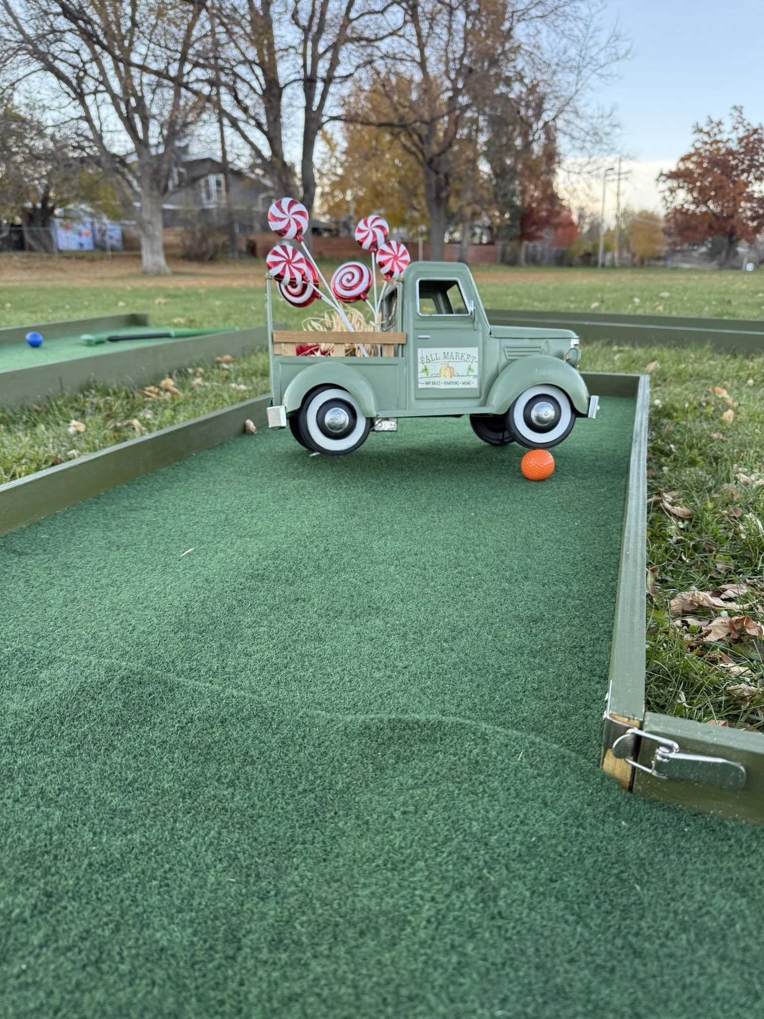 Mobile mini golf course with miniature vintage farm truck filled with red and white peppermint swirl candies.