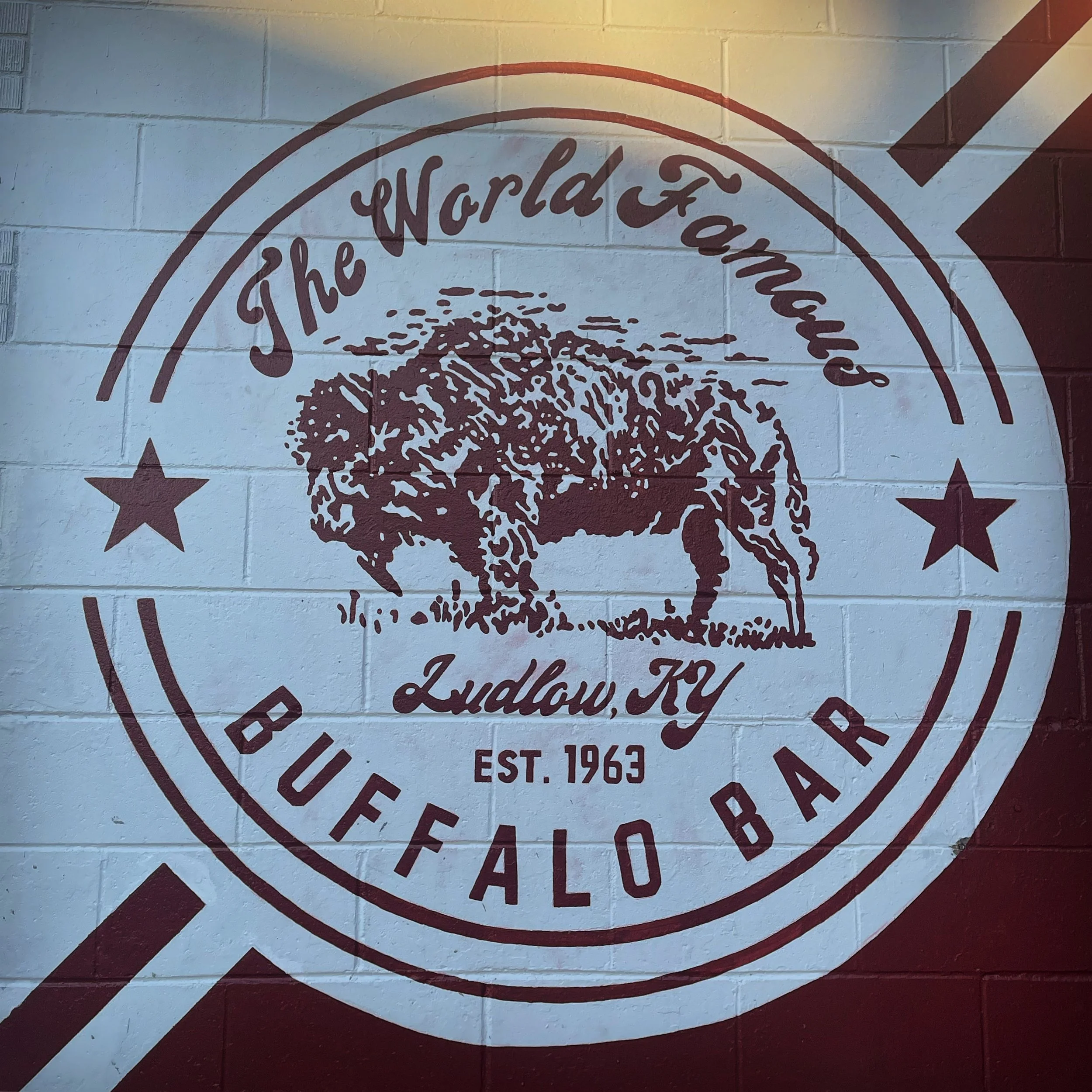 Wall mural advertising The World Famous Buffalo Bar in Ludlow, KY, established in 1963, with a large buffalo illustration and circular text design.