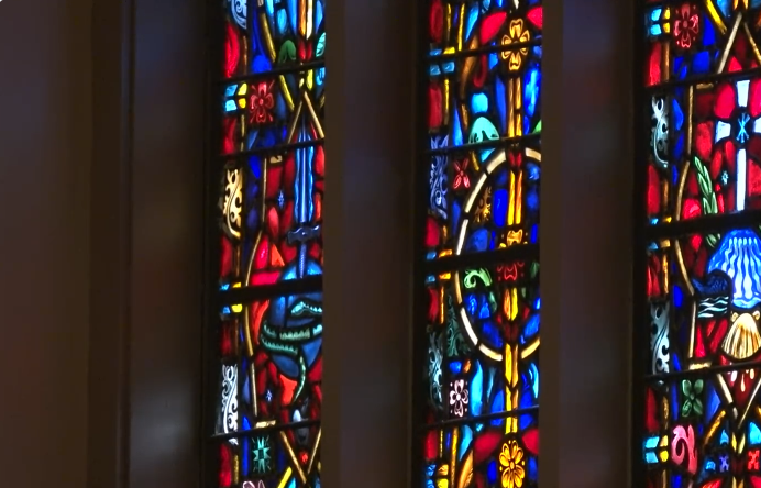 Colorful stained glass windows with various religious symbols and floral designs.
