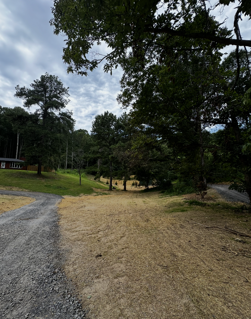 Completed land clearing and site preparation project with improved gravel driveway and cleared property