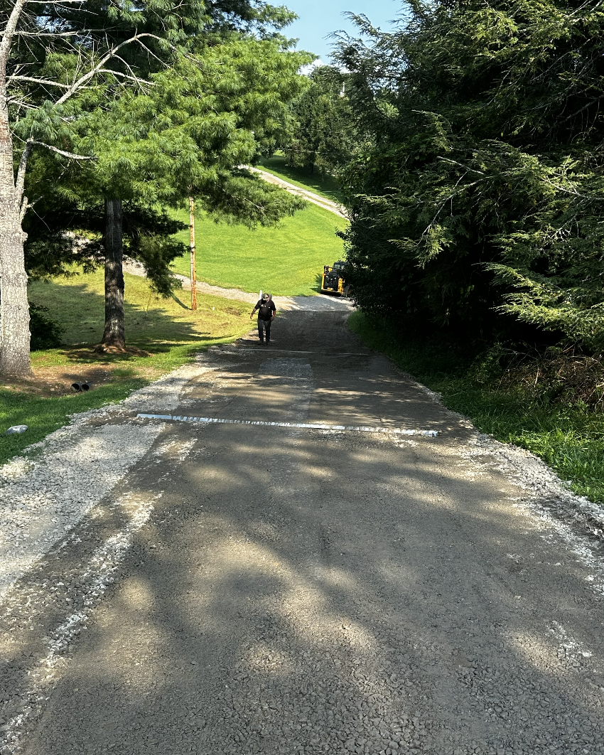 Fresh gravel driveway being graded and compacted during a driveway improvement project