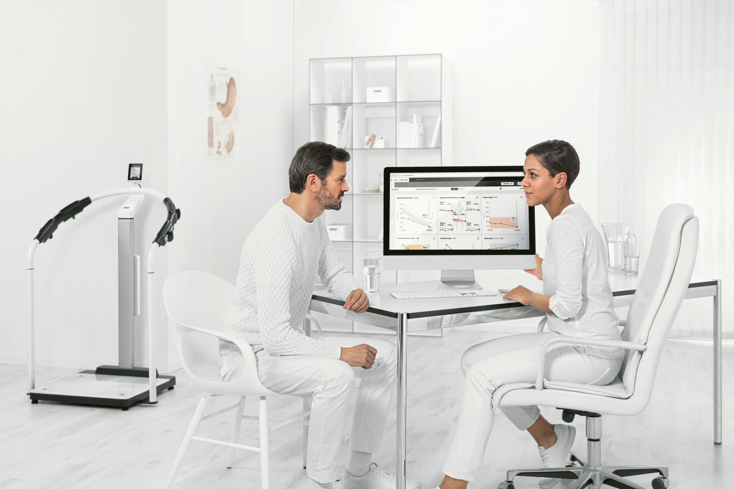 Bright clinic space with a registered nurse consulting with a client at a desk with a computer.