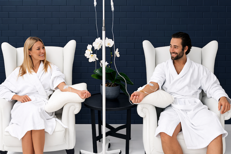 Happy couple receiving infusions in a bright lit clinic space.