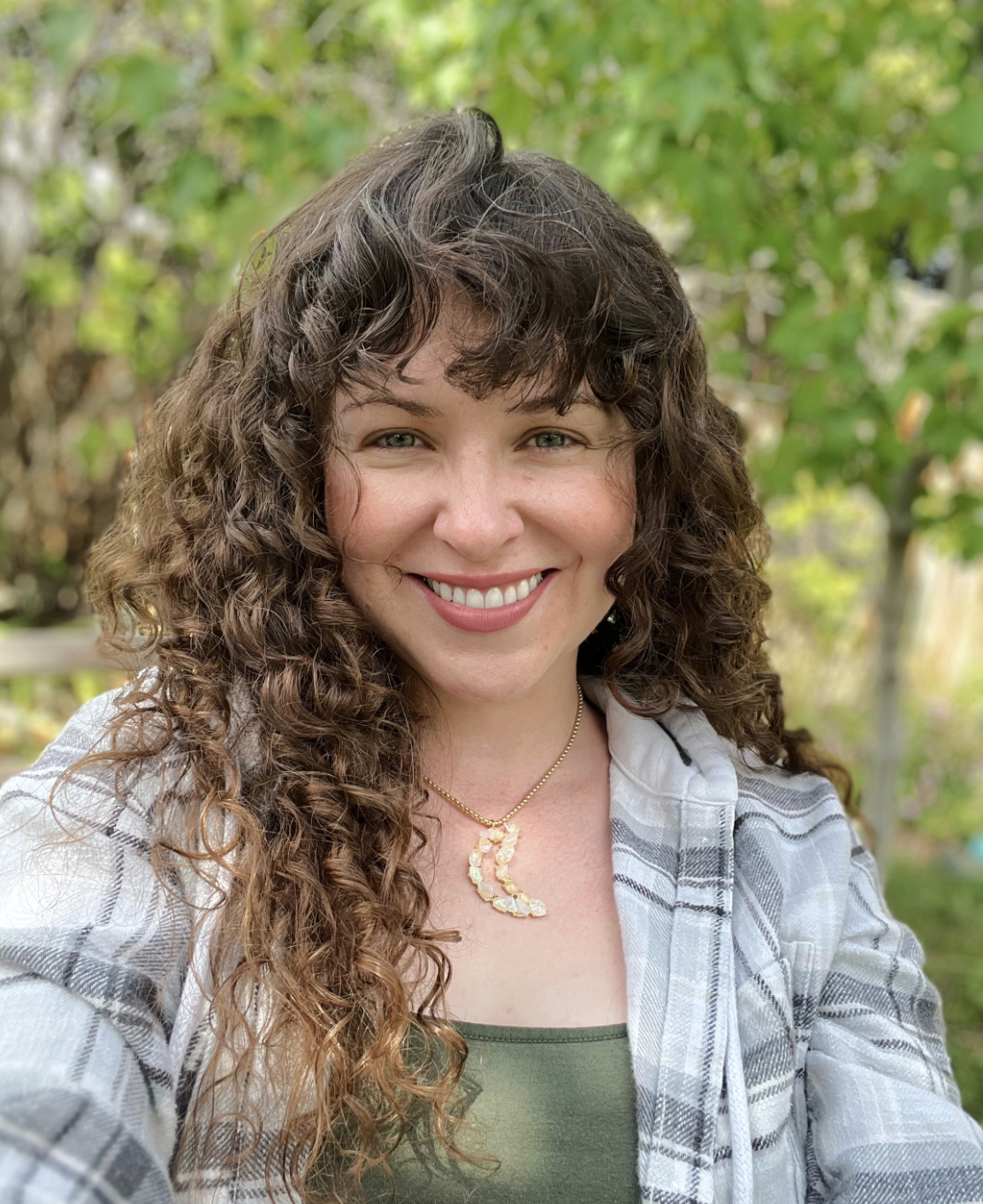 psychic medium Rachel smiling outside beneath green trees