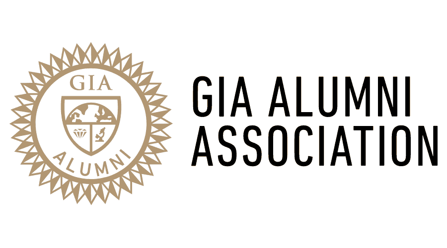 Logo of GIA Alumnae Association with a gold emblem featuring a shield divided into four sections and a sunburst design surrounding it, next to the text 'GIA Alumnae Association' in black.