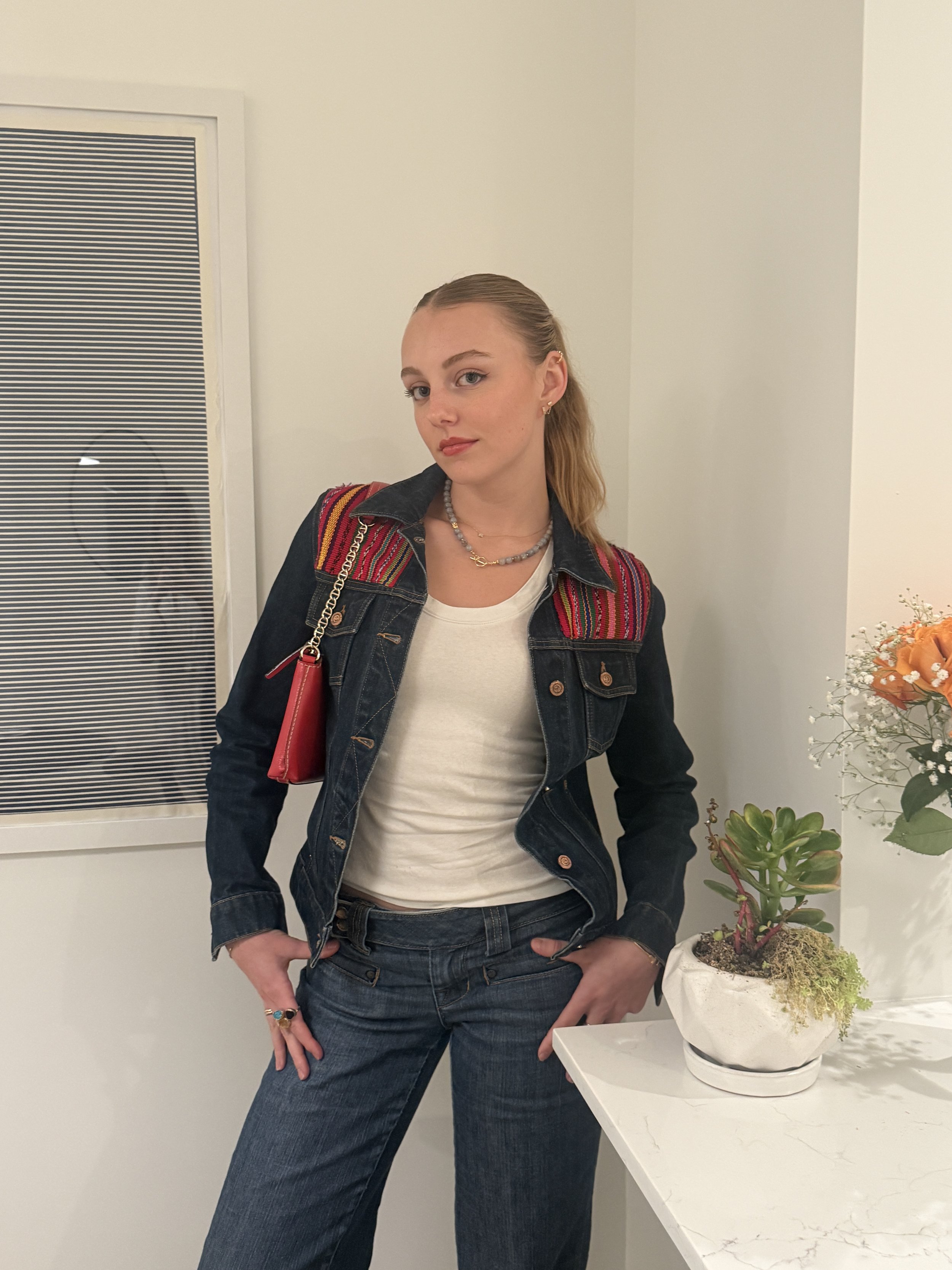 Woman wearing the Mariny necklace in the shade lavender. She's wearing jeans with an embroidered jean jacket and the handmade beaded necklace to tie the look together