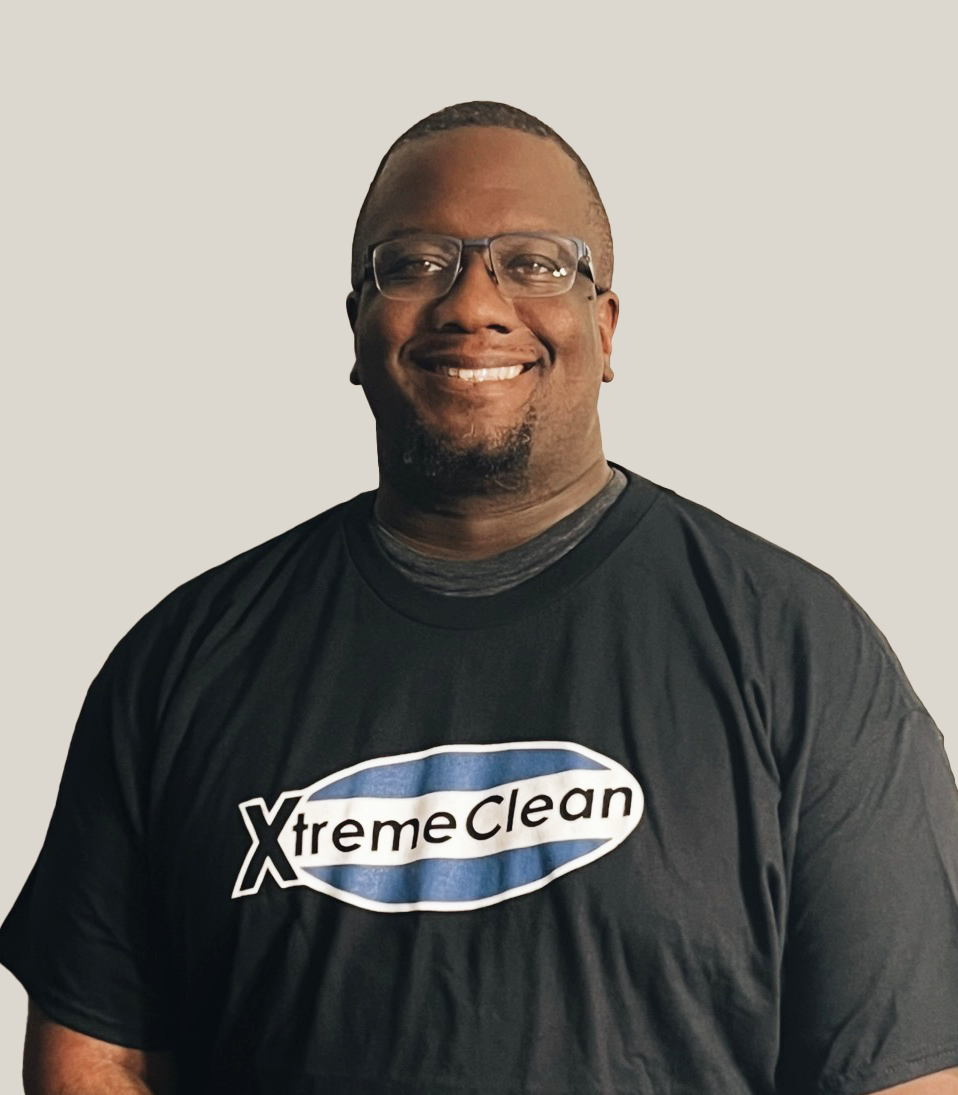 Smiling man wearing glasses and a black t-shirt with 'XtremeClean' logo, standing against a plain background.