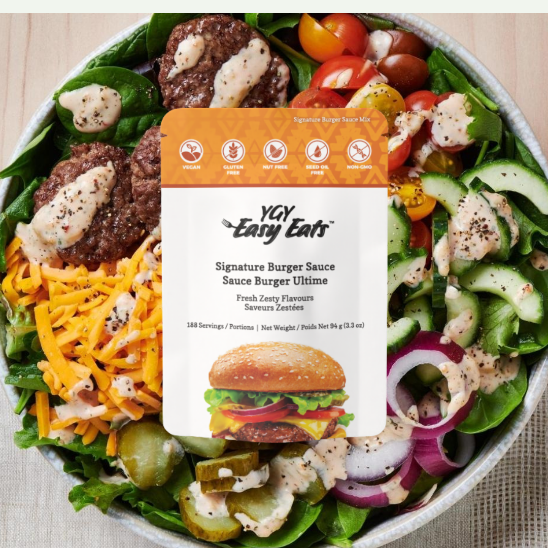 A large salad with cherry tomatoes, cucumber, red onion, pickles, lettuce, shredded cheddar cheese, cooked burger patties with cheese, and salad dressing in a bowl with a label from YAY Easy Eats on top.