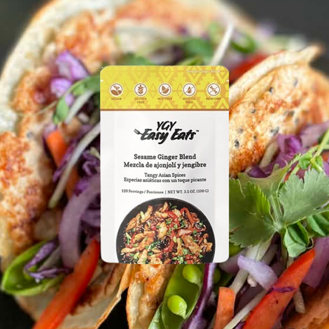 A package of Yay Easy Eats Sesame Ginger Blend seasoning placed over a vegetable salad with grilled chicken, purple cabbage, carrots, and greens.