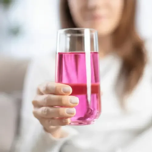 Person holding a glass of pink liquid with a straw, hydration is important with healthy choose.