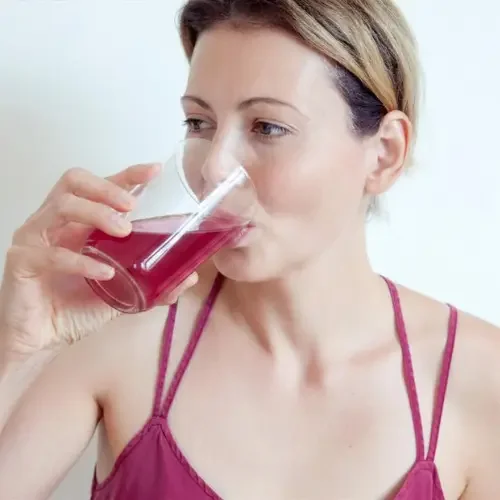 Woman drinking a pink beverage from a clear glass