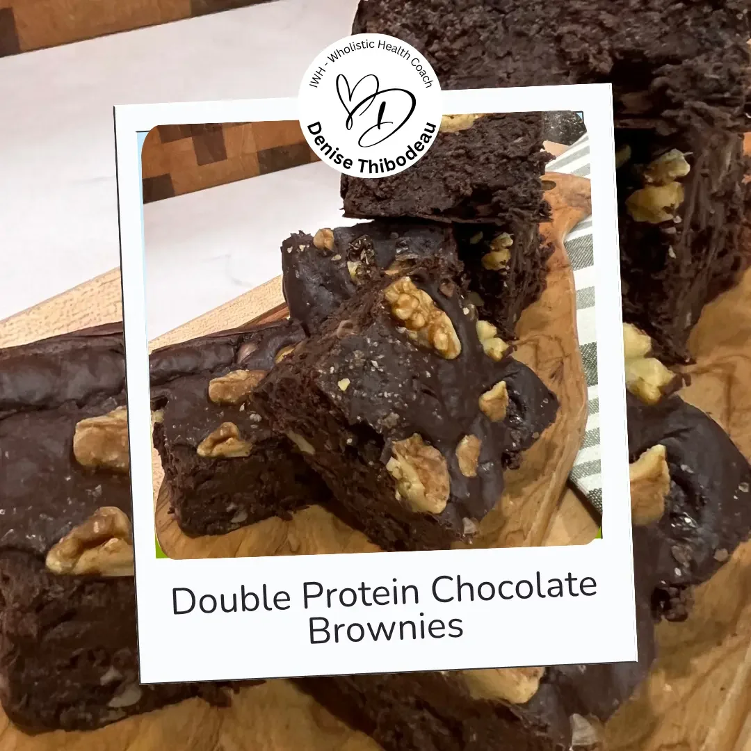 Close-up of double protein chocolate brownies topped with walnuts on a wooden cutting board.