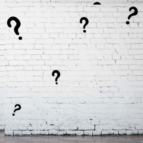 White brick wall with black question marks attached.