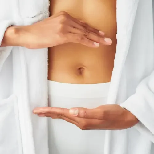 Close-up of a person's torso, hands forming a rectangular shape around the stomach area, wearing a white robe or shirt.