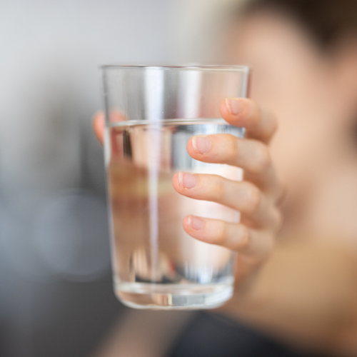 Person holding a clear glass of water.