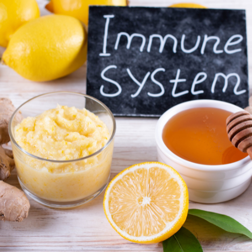 Lemon, ginger, honey, and lemon juice in bowls and glass, with a chalkboard sign reading 'Immune System'