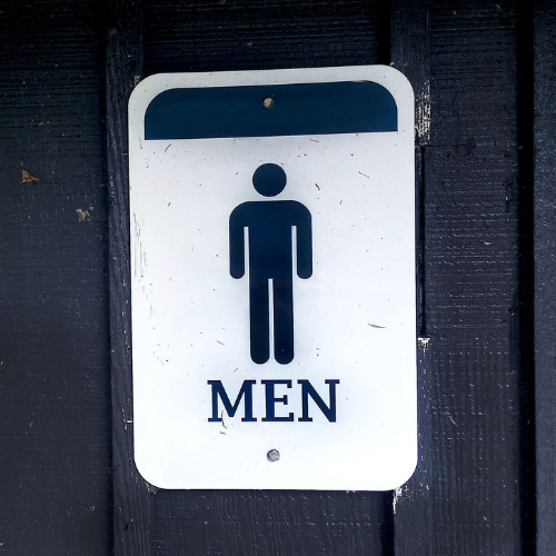 Men's restroom sign on a dark wooden surface.