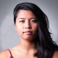 A woman with long black hair wearing a red tank top against a gray background.