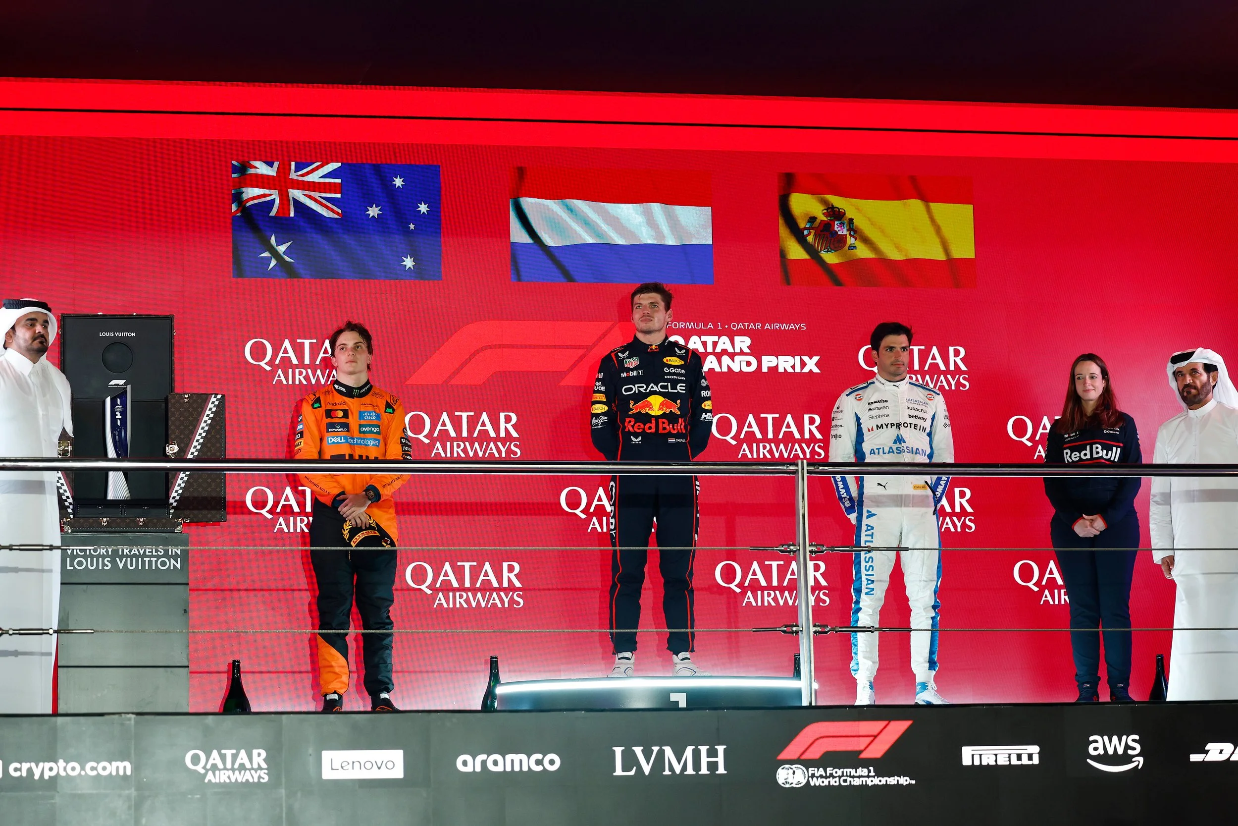 Carlos Sainz standing with Max Verstappen and Oscar Piastri on the 2025 Qatar Grand Prix podium