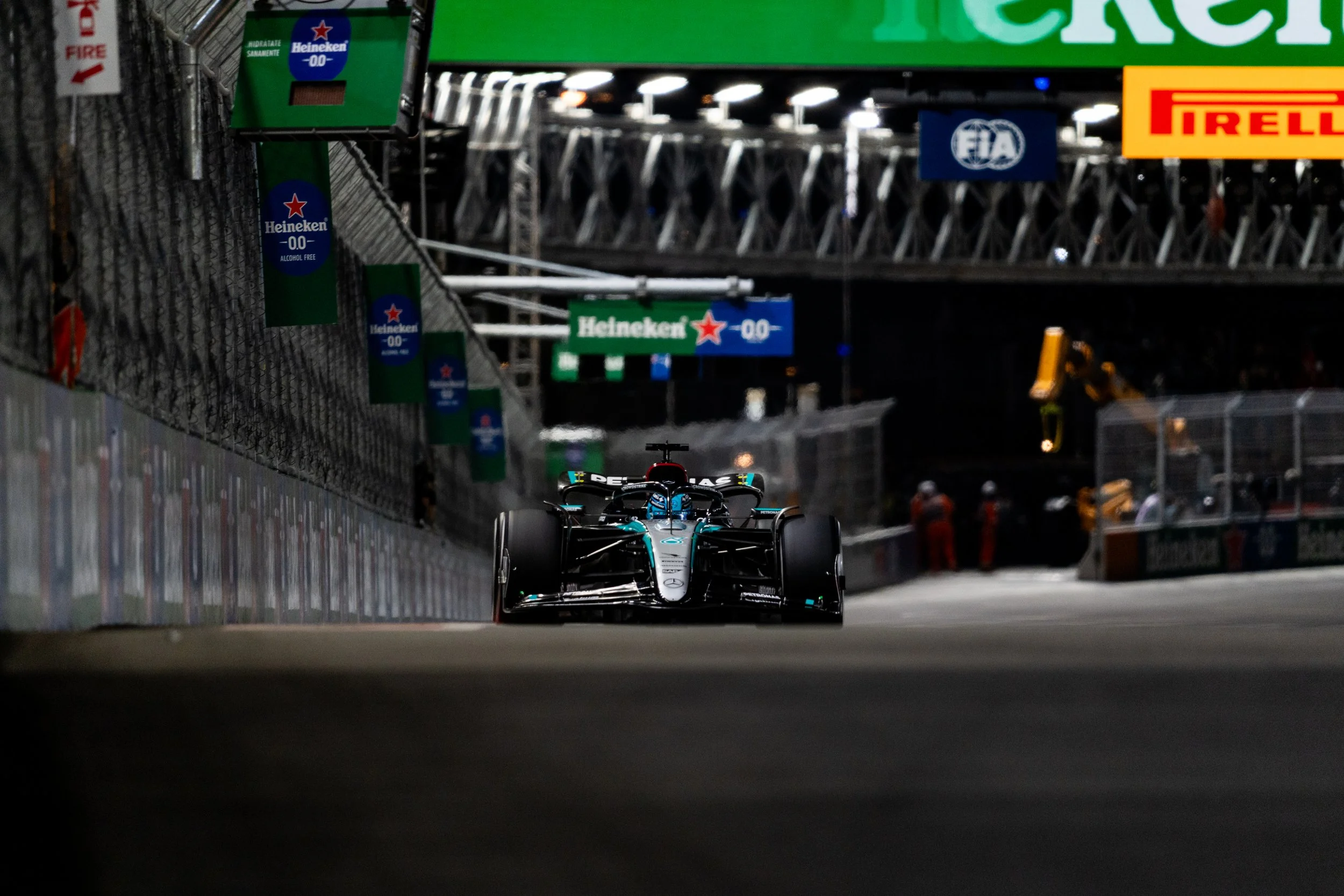 Mercedes AMG Petronas Formula 1 race car on a track during a night race in Las Vegas Grand Prix, with advertisements and barriers visible along the sides.