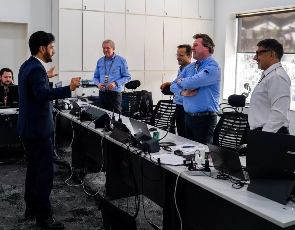 Mohammed Ben Sulayem speaking with FIA personnel in a motorsport operations room.