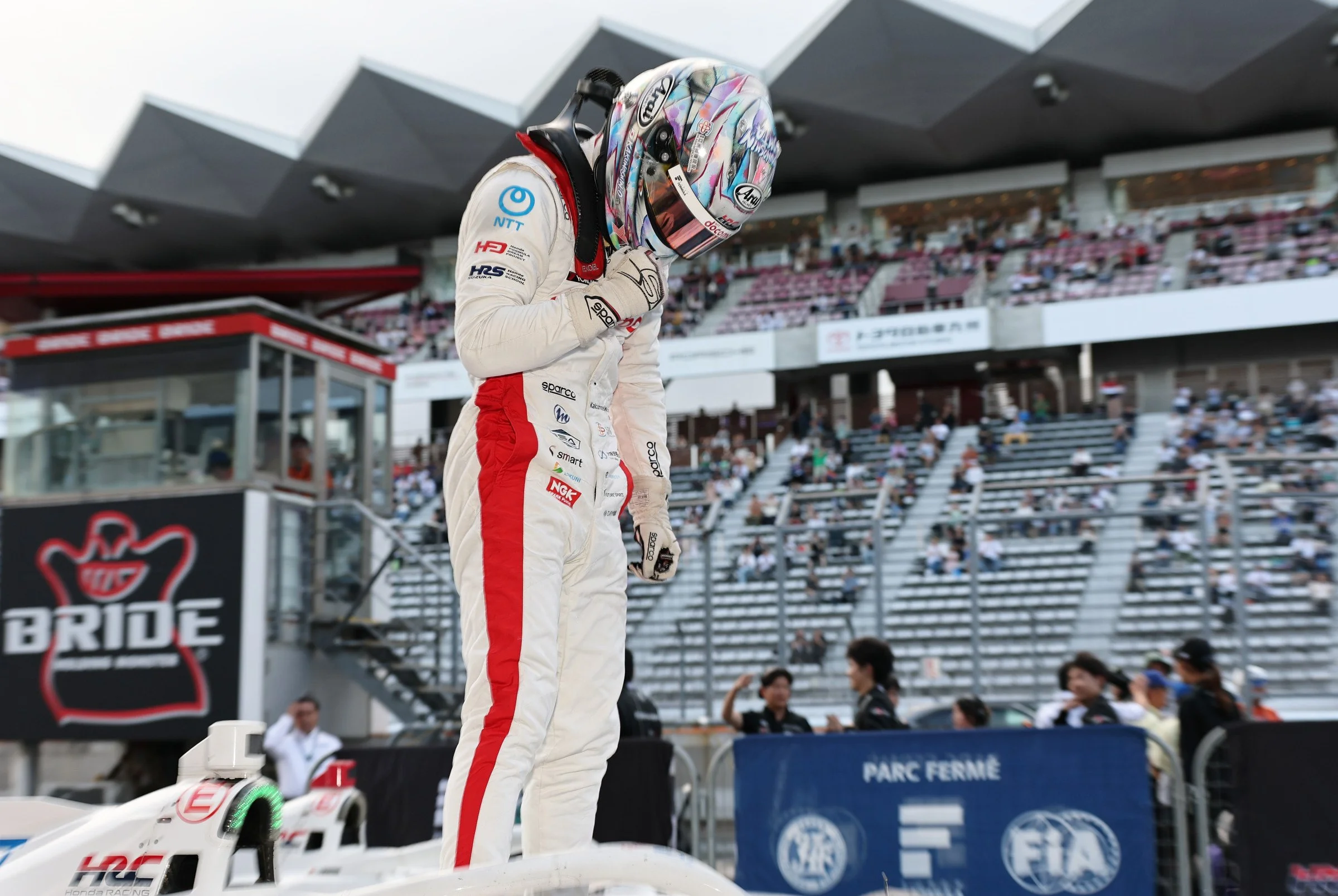 Kakunoshin Ohta celebrates while standing on his Dandelion Racing car after a Super Formula victory.