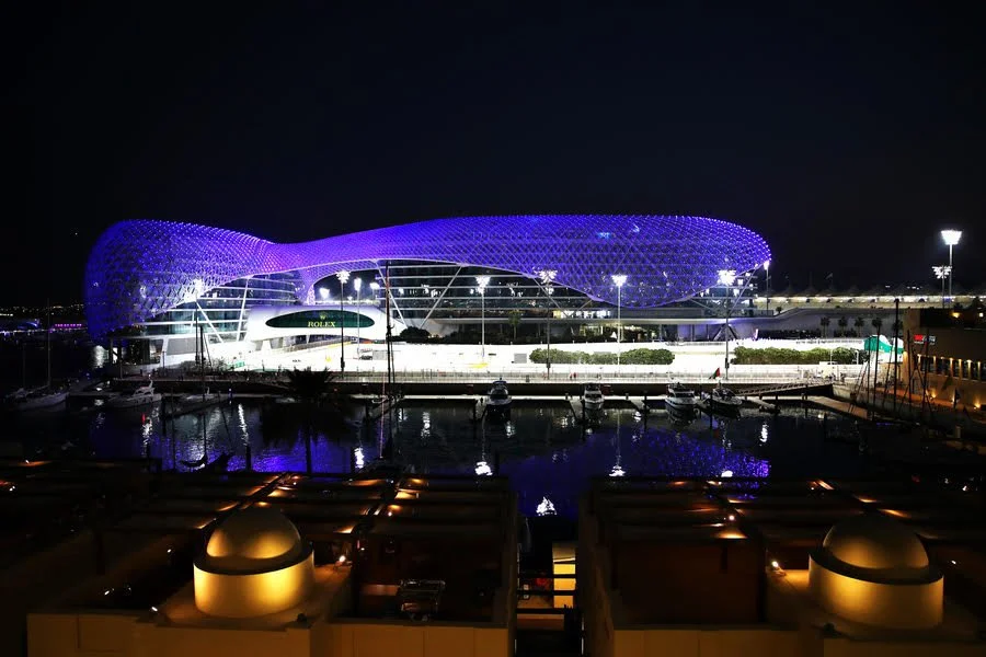 The purple-lit Yas Marina Circuit hotel reflected in the marina at night in Abu Dhabi.