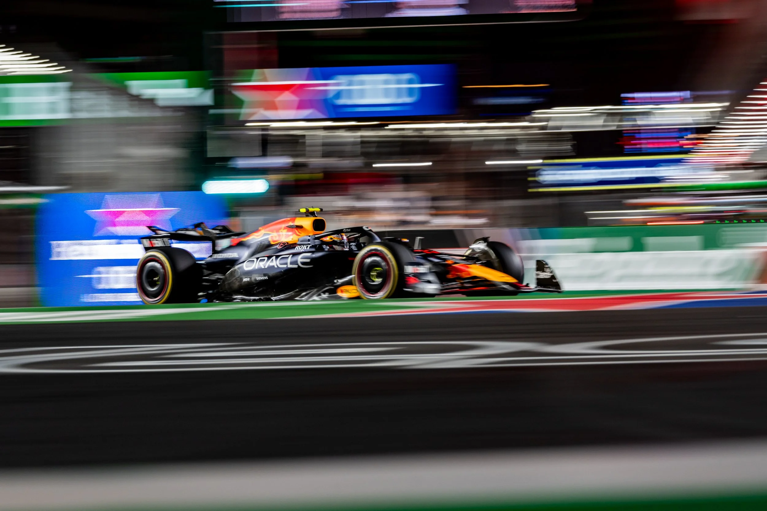 Red Bull Formula 1 car on scene at Formula 1 Las Vegas GP race car speeding on a race track, with motion blur in the background, sponsored by Oracle and Red Bull Racing, on a brightly lit street circuit.