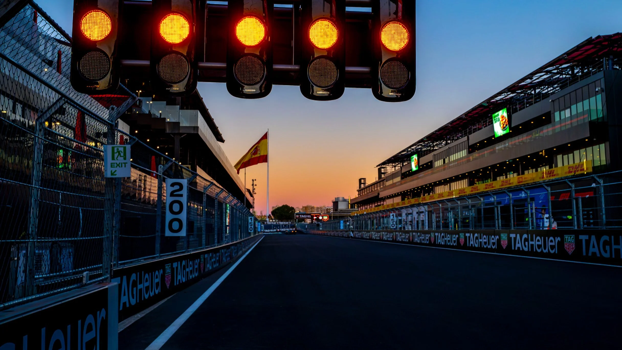MADRING start-finish straight beneath illuminated Formula 1 start lights at sunset