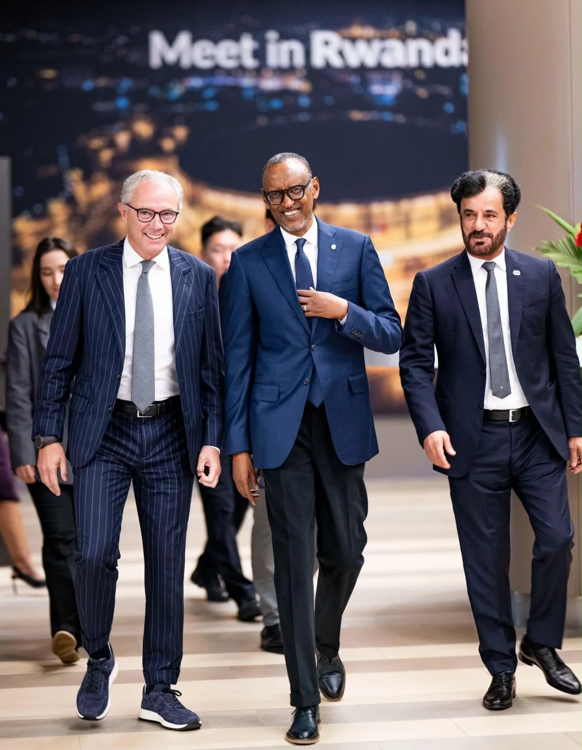 Formula 1 CEO Stefano Domenicali walks alongside Rwandan President Paul Kagame and FIA President Mohammed Ben Sulayem inside an event venue in Kigali.