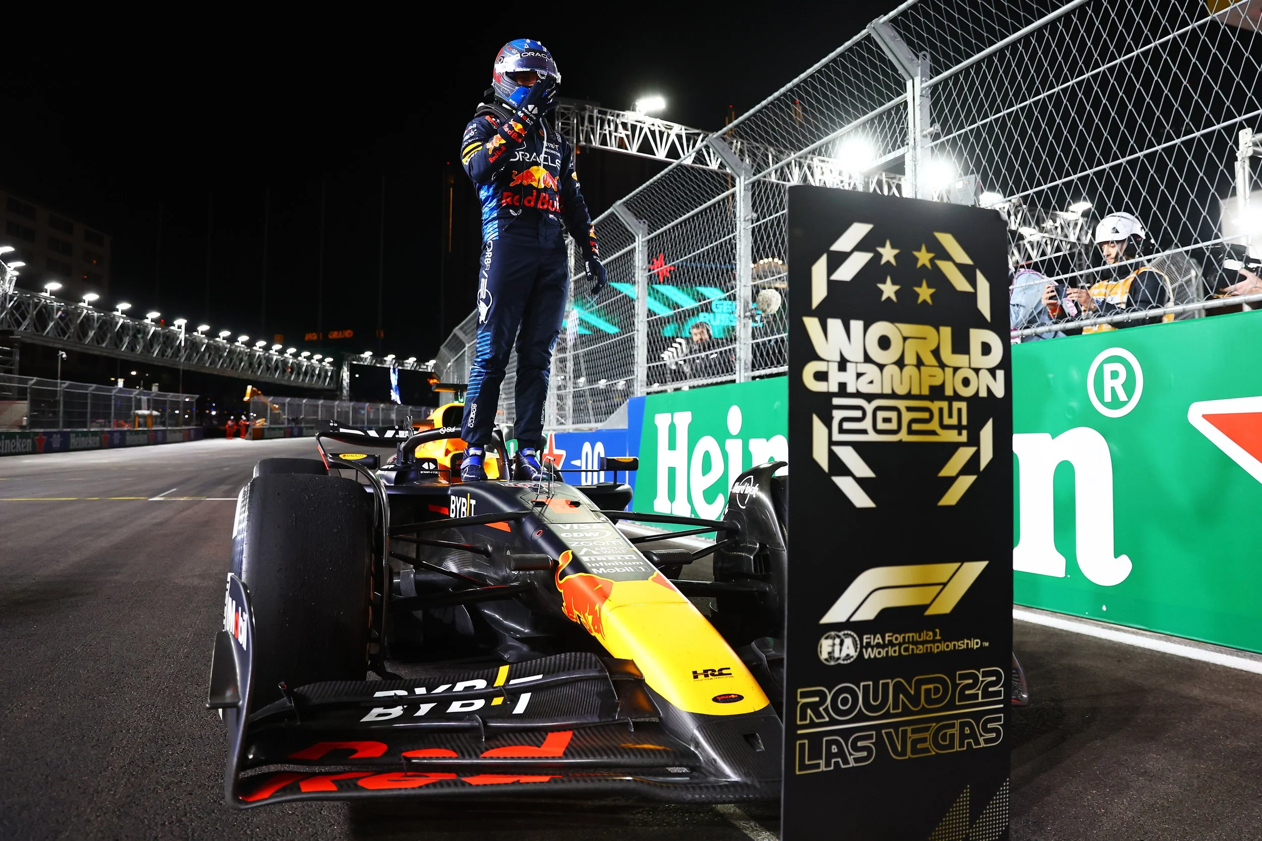 Max Verstappen stands on his Red Bull Racing car beside the 2024 Formula 1 World Champion sign in Las Vegas.