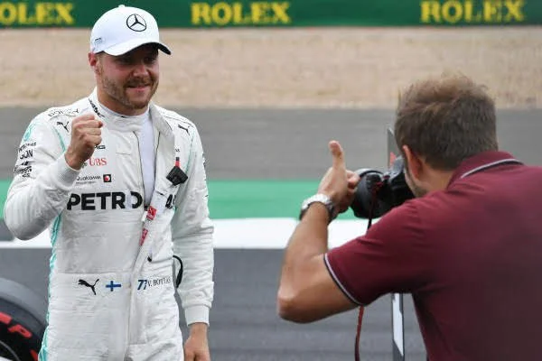 Formula 1 driver Lewis Hamilton celebrating with a fist pump after a race, being photographed by a photographer on the race track.