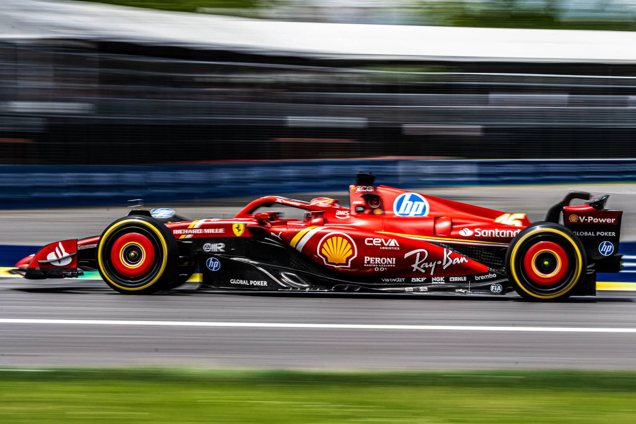 Ferrari F1 car with sponsor logos driving on a race track, showing motion blur background.