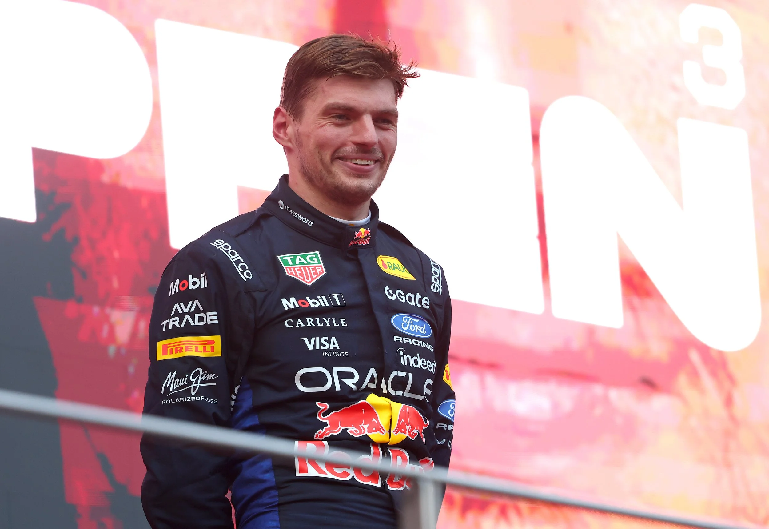 Max Verstappen smiling on the podium in his Red Bull racing suit after winning at Sepang in 2026.