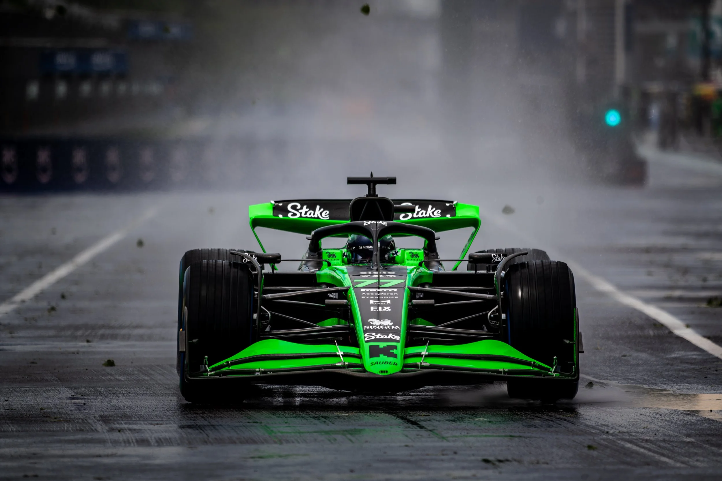 Stake F1 Team at Canadian GP on wet racetrack during rain with water spray.