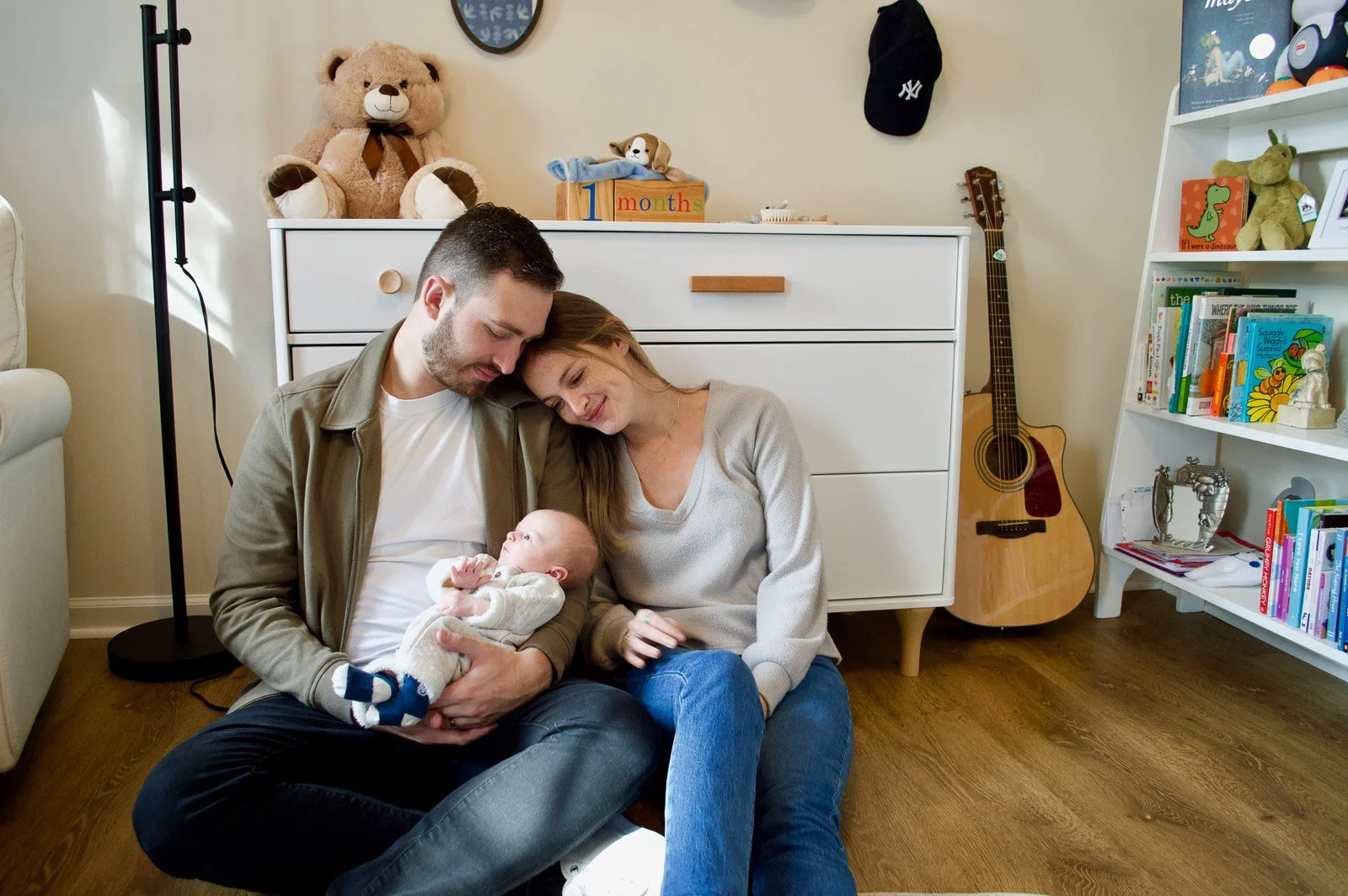 A family of three sitting on the floor in a nursery. Family photography. Newborn photography. Portrait photography.