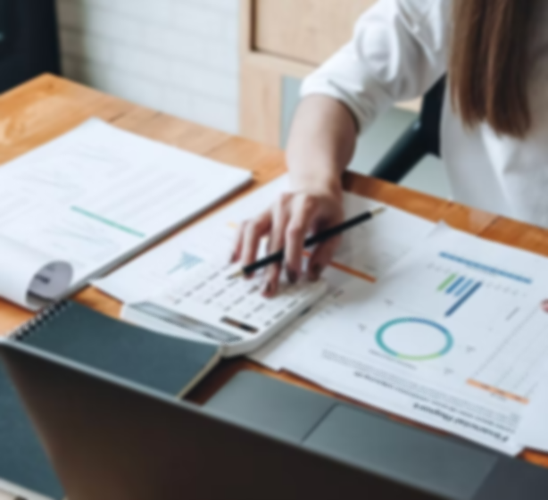 Person working with financial charts and documents on a wooden desk